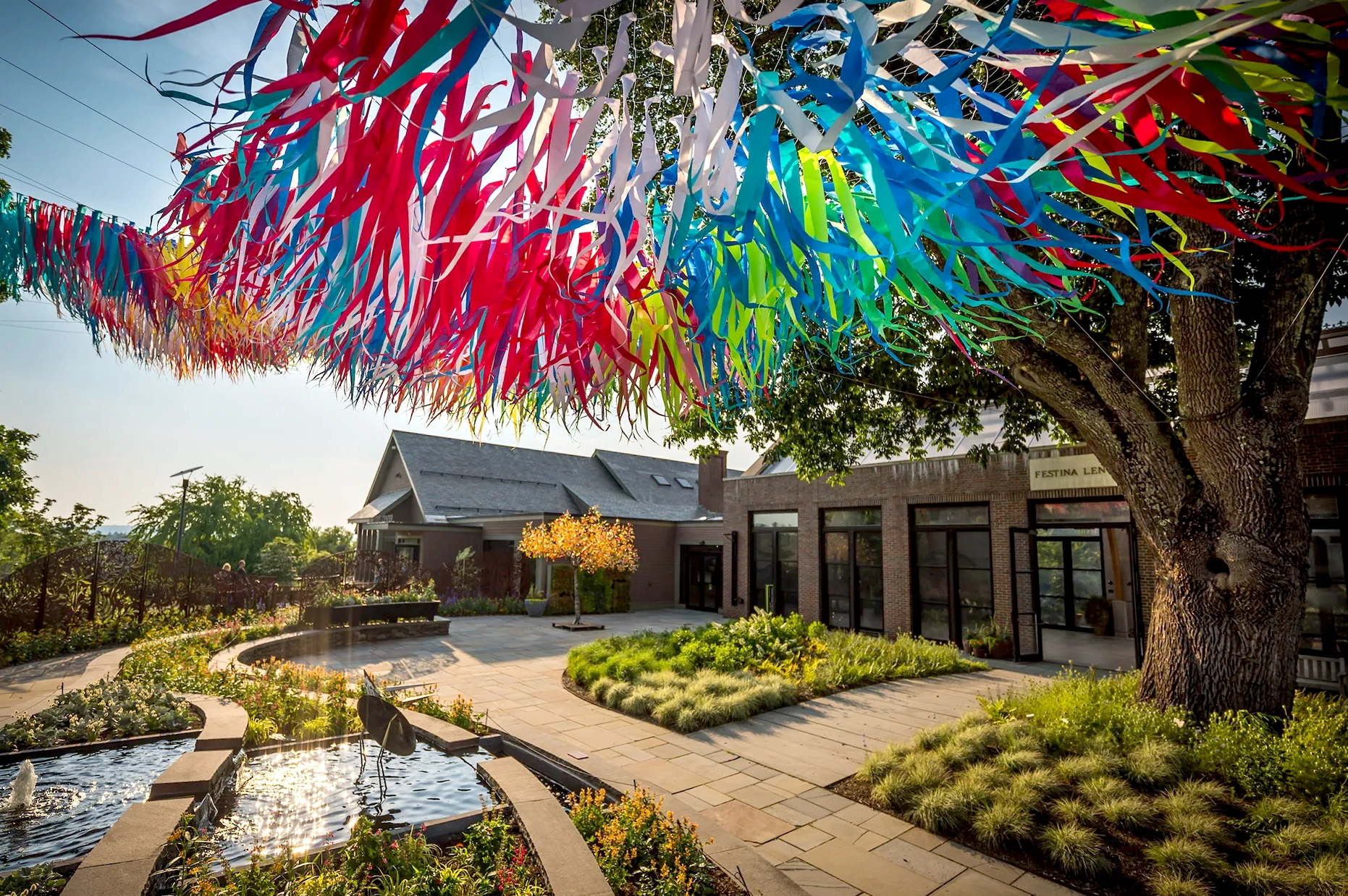 Wild movement of Poetic Kinetics' vibrant 'Flora in Flight' suspended over the courtyard at New England Botanic Garden.